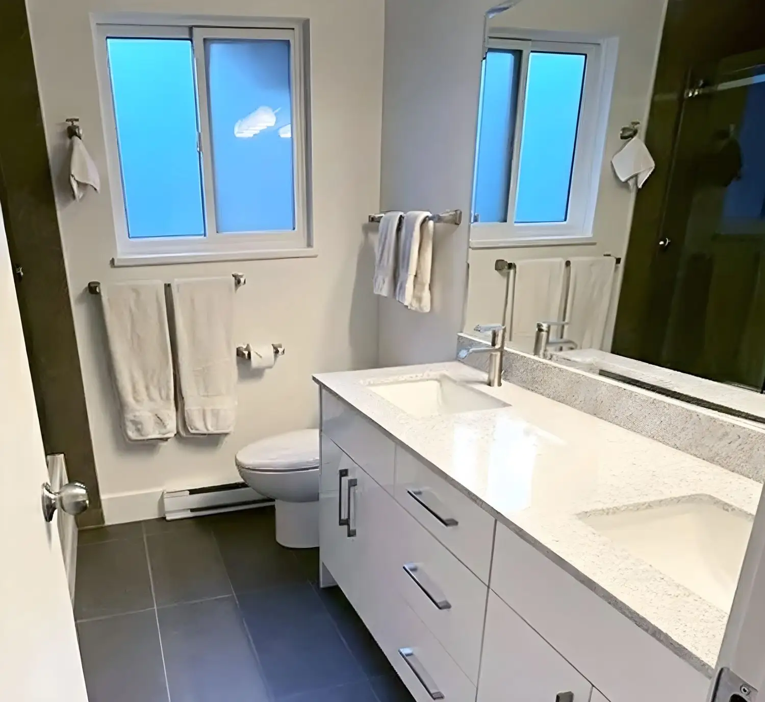 Reforma de baño con mueble de doble lavabo blanco y encimera de piedra clara en Barcelona