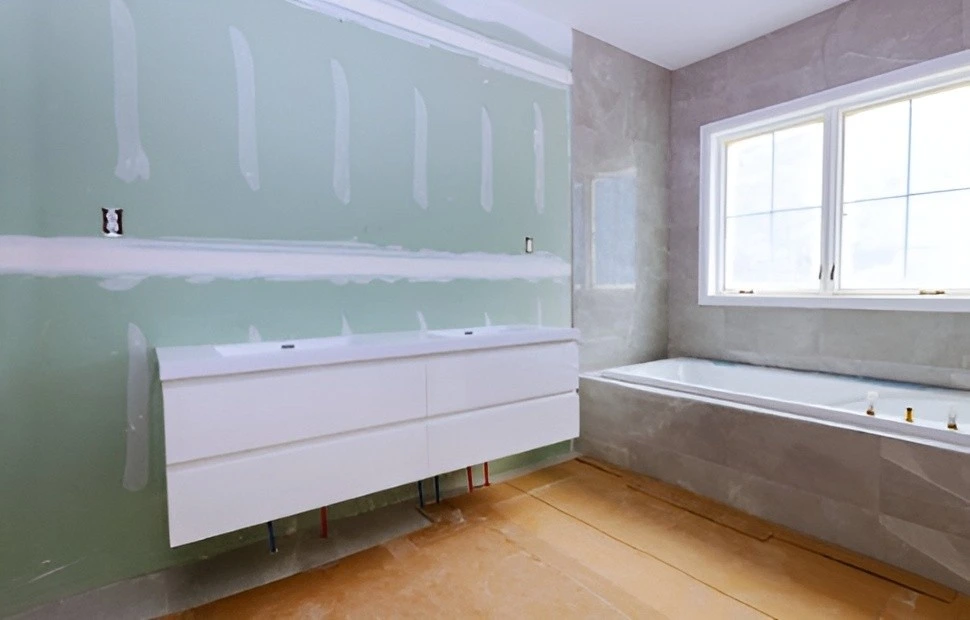 Reforma de baño con mueble suspendido blanco sobre pared de pladur en proceso en Barcelona