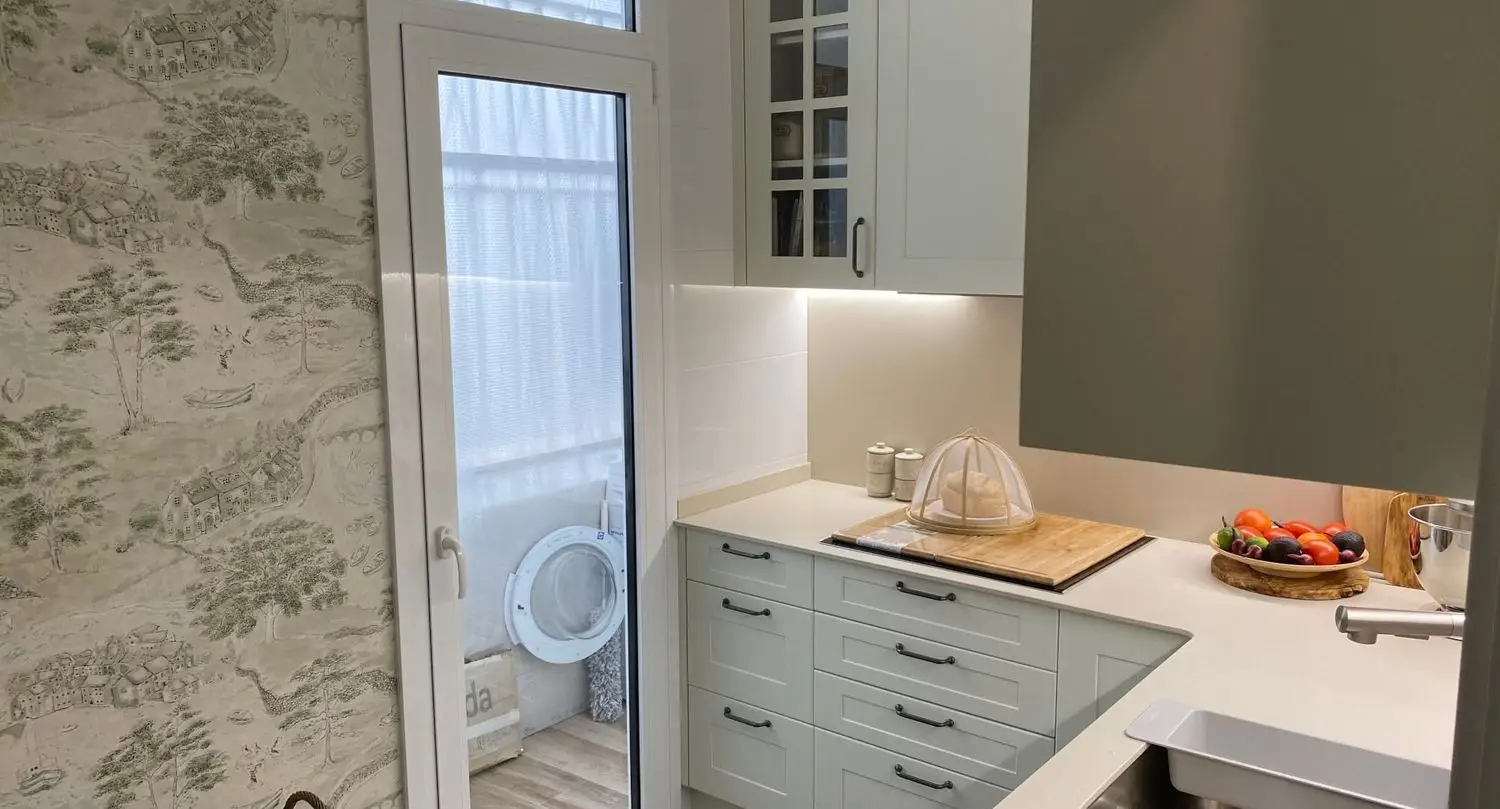Reforma cocina con mobiliario blanco de estilo clásico y papel pintado decorativo en Barcelona